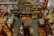 An overhead view of a cluttered antique store filled with various items. Shelves are stocked with vintage pottery, teapots, and glassware, while tables display decorative plates, vases, and lamps. There are wooden furniture pieces, small baskets, and books scattered throughout the space. A variety of eclectic and nostalgic objects create a sense of organized chaos.