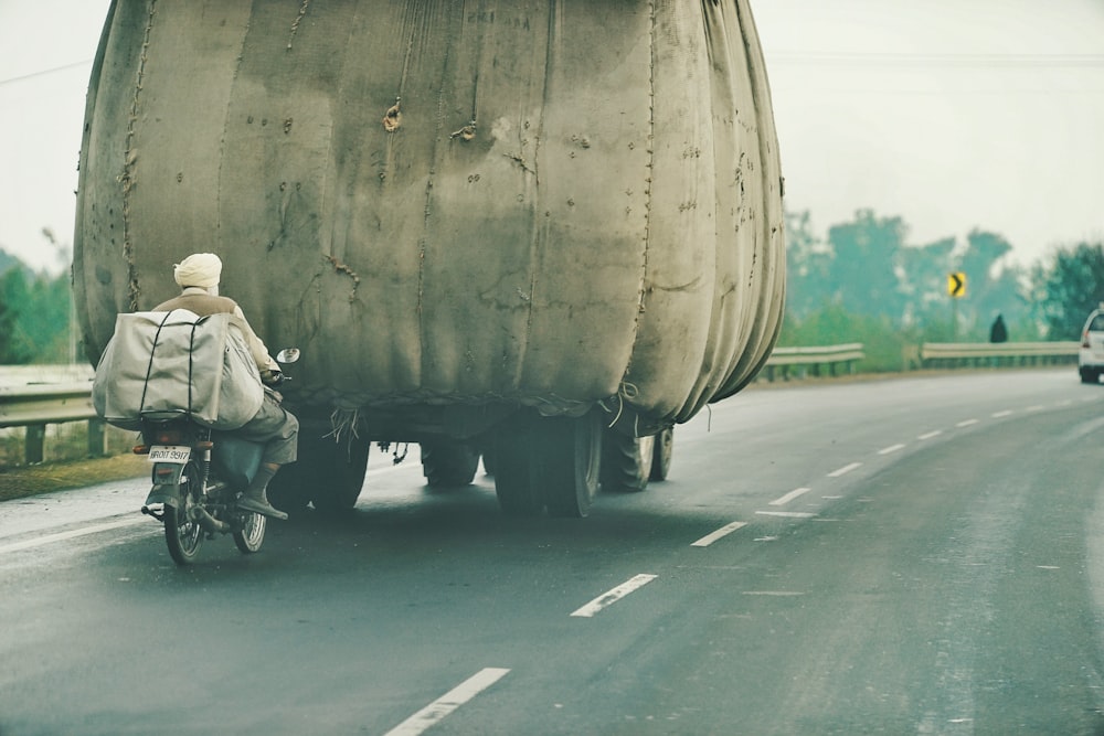 a person riding a motorcycle next to a large container