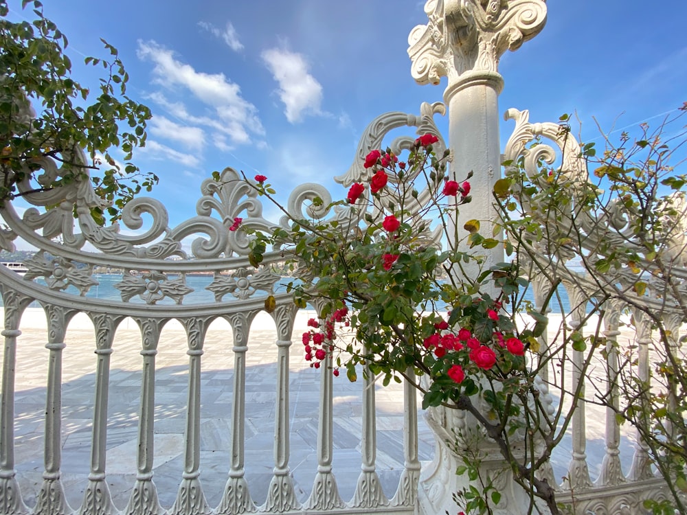 a white fence with flowers and a statue on top