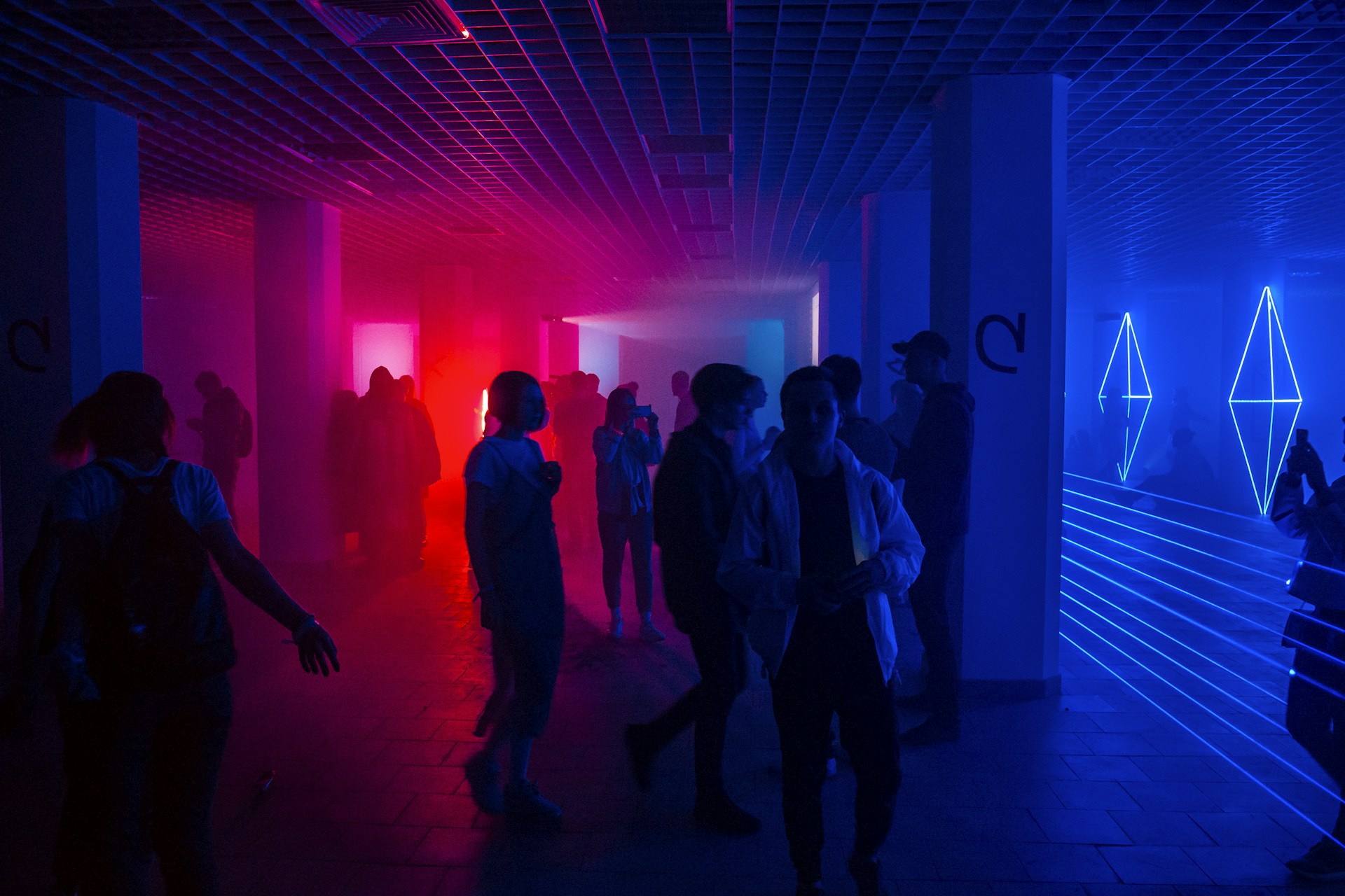 a group of people walking through a room with bright lights