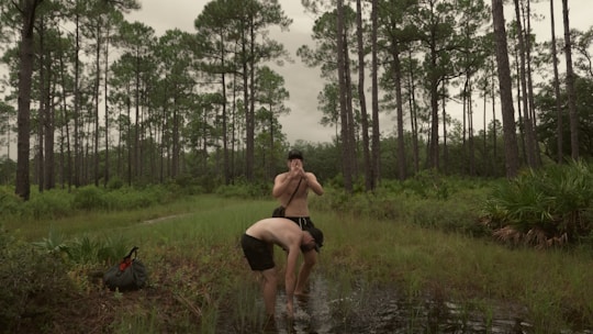 A warm, natural scene with someone washing hands outdoors near a tree.
