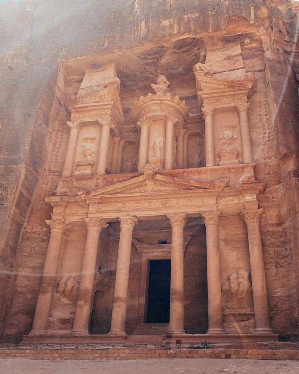 a large stone building with pillars with Petra in the background