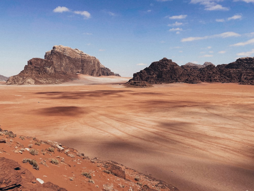 a desert landscape with a few large rocks with Wadi Rum in the background