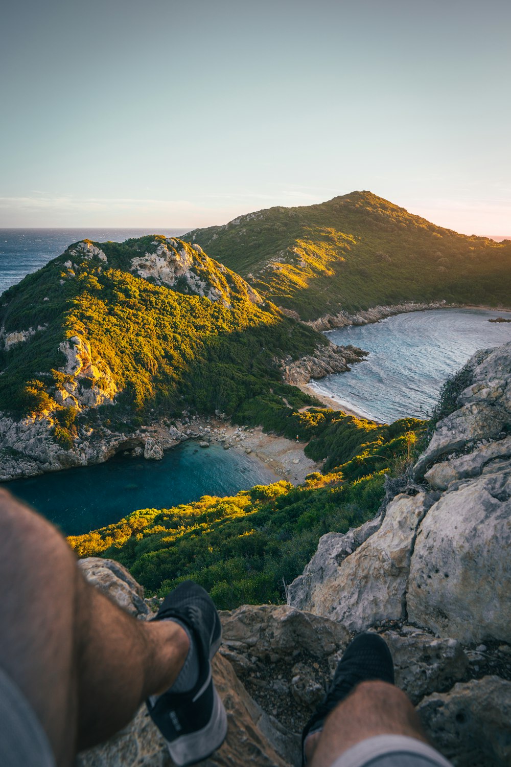 a person's feet on a rock ledge overlooking a body of water