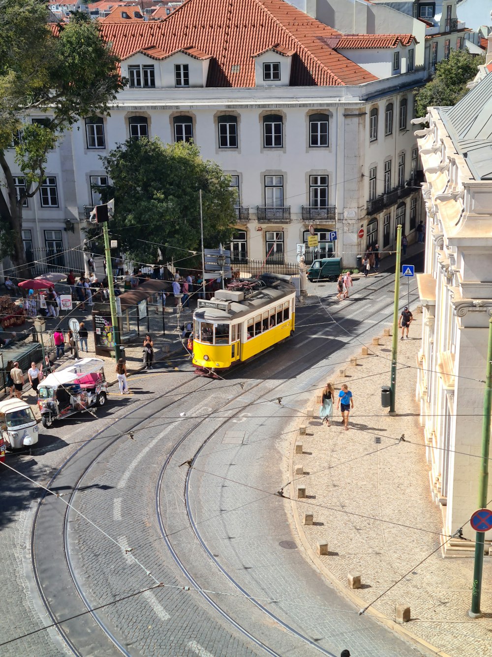 a yellow and white bus driving down a street next to tall buildings