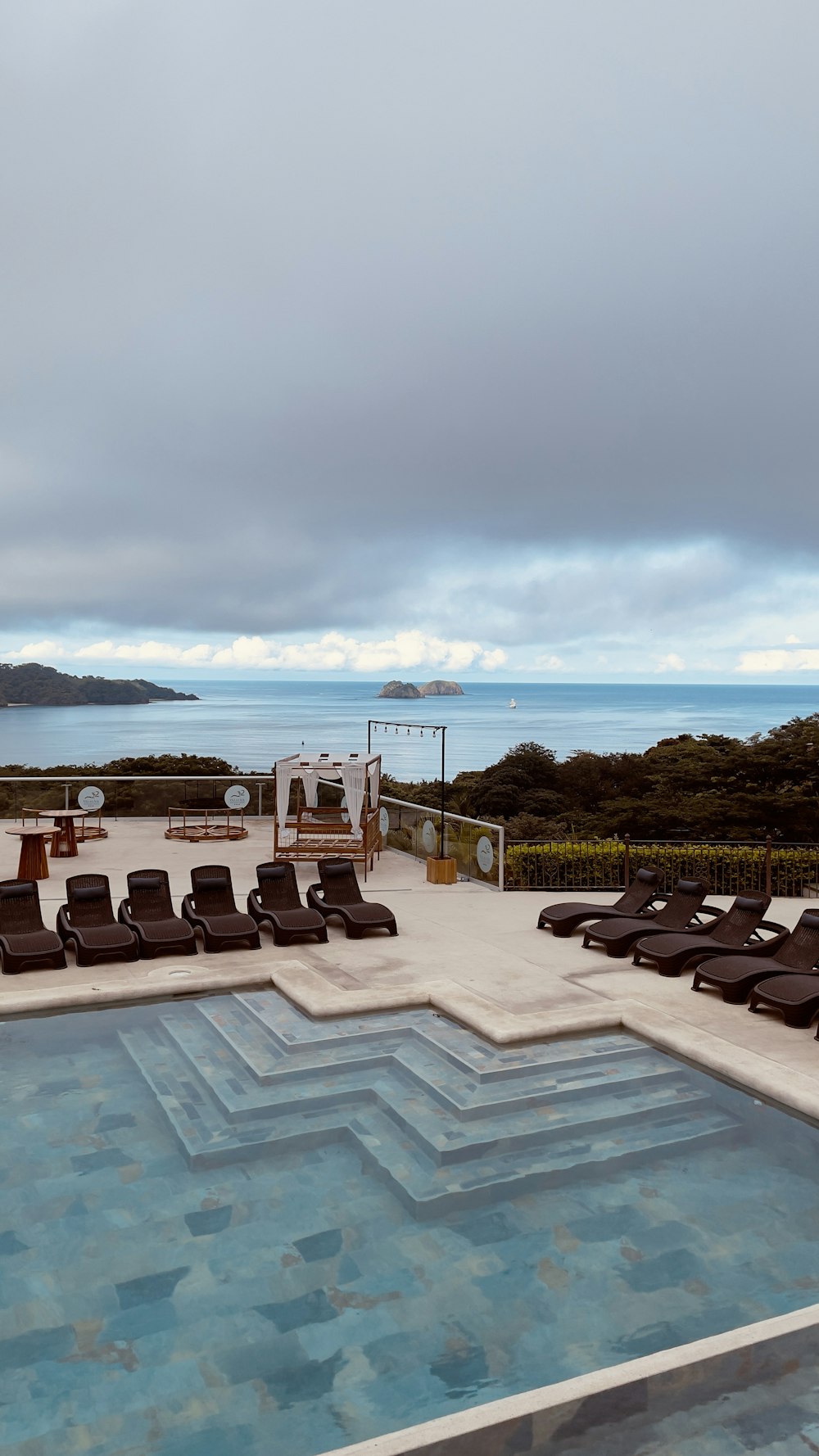 a pool with chairs around it by a body of water