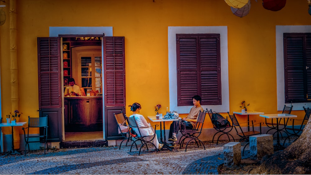 a group of people sitting at a table in a room with a yellow wall and a red door