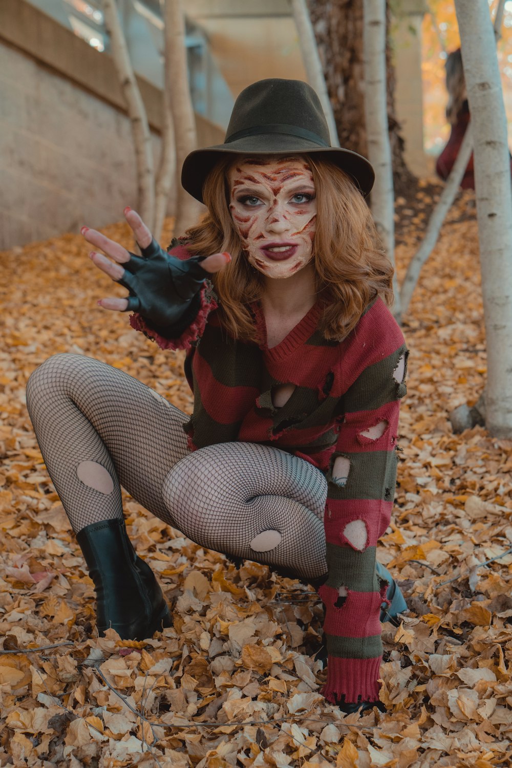 a woman wearing a hat and sitting on leaves