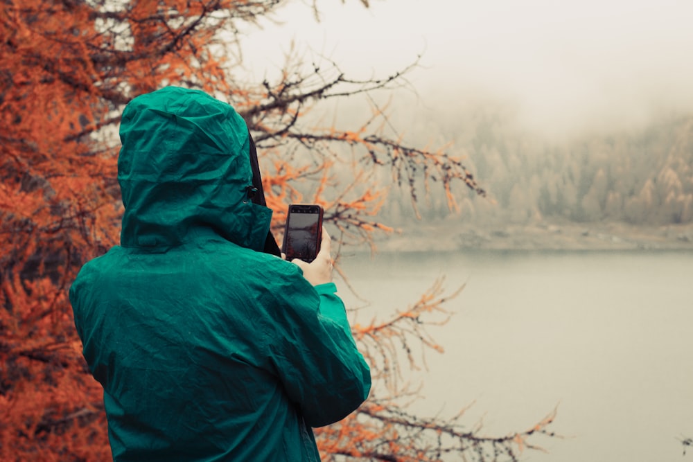 a person wearing a green jacket and holding a cell phone