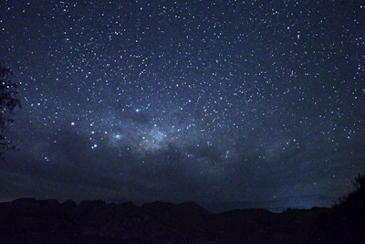 A star-filled night sky above the eco lodge, framed by silhouetted mountains.