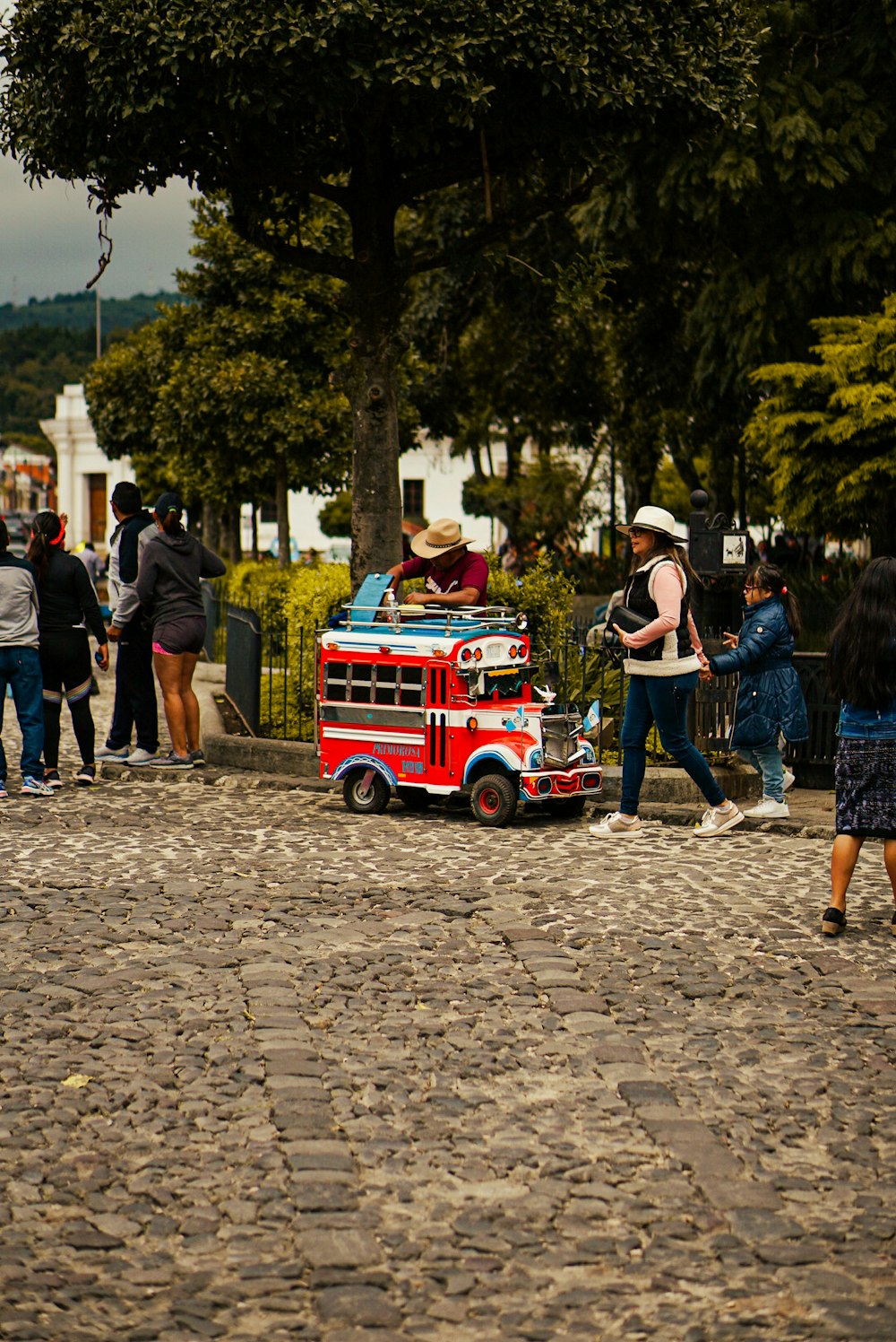 a group of people standing around a small red truck