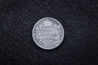 An antique coin featuring a historic emblem from India.