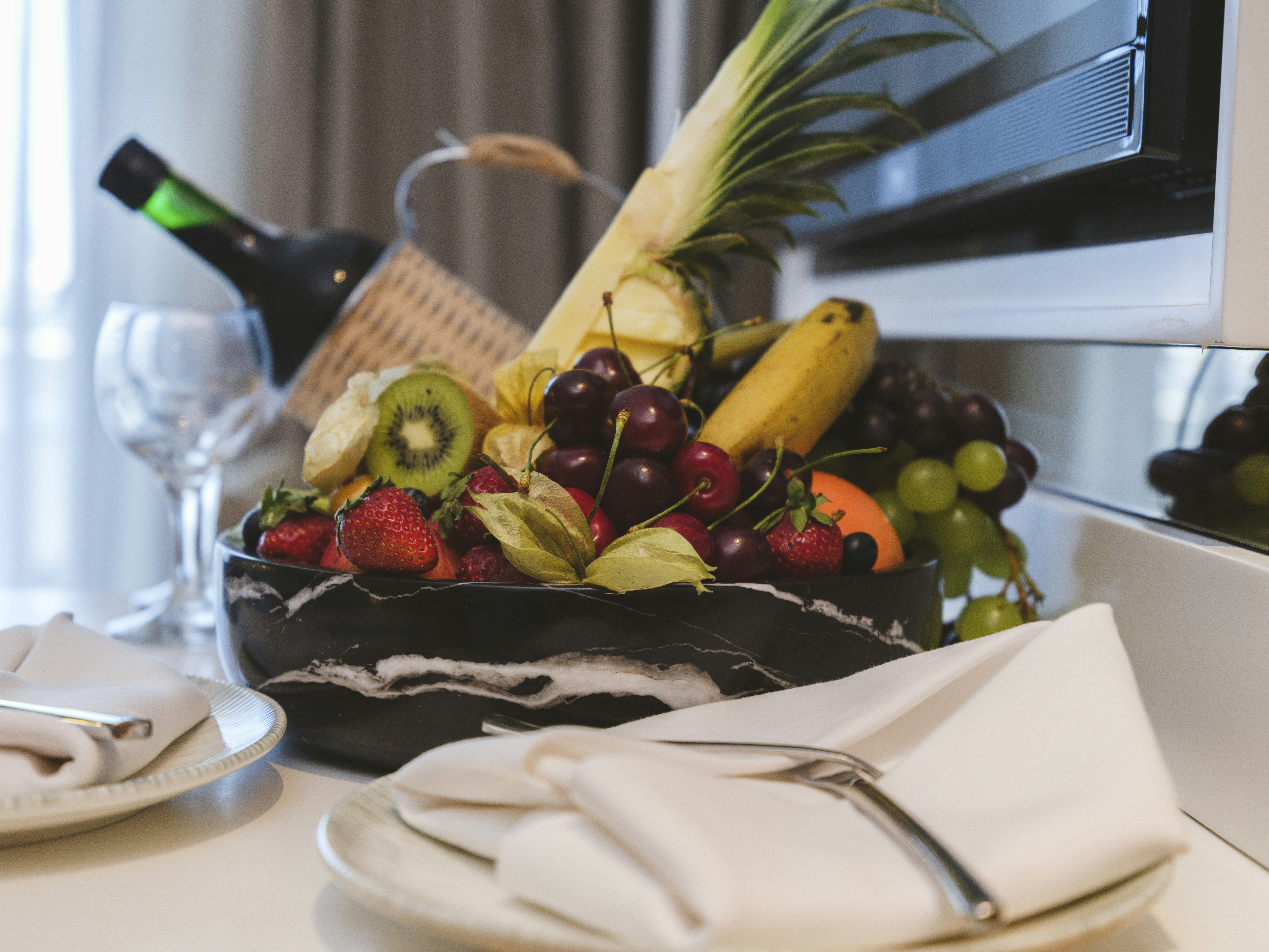 a plate of fruit, tropical fruits and wine in hotel room