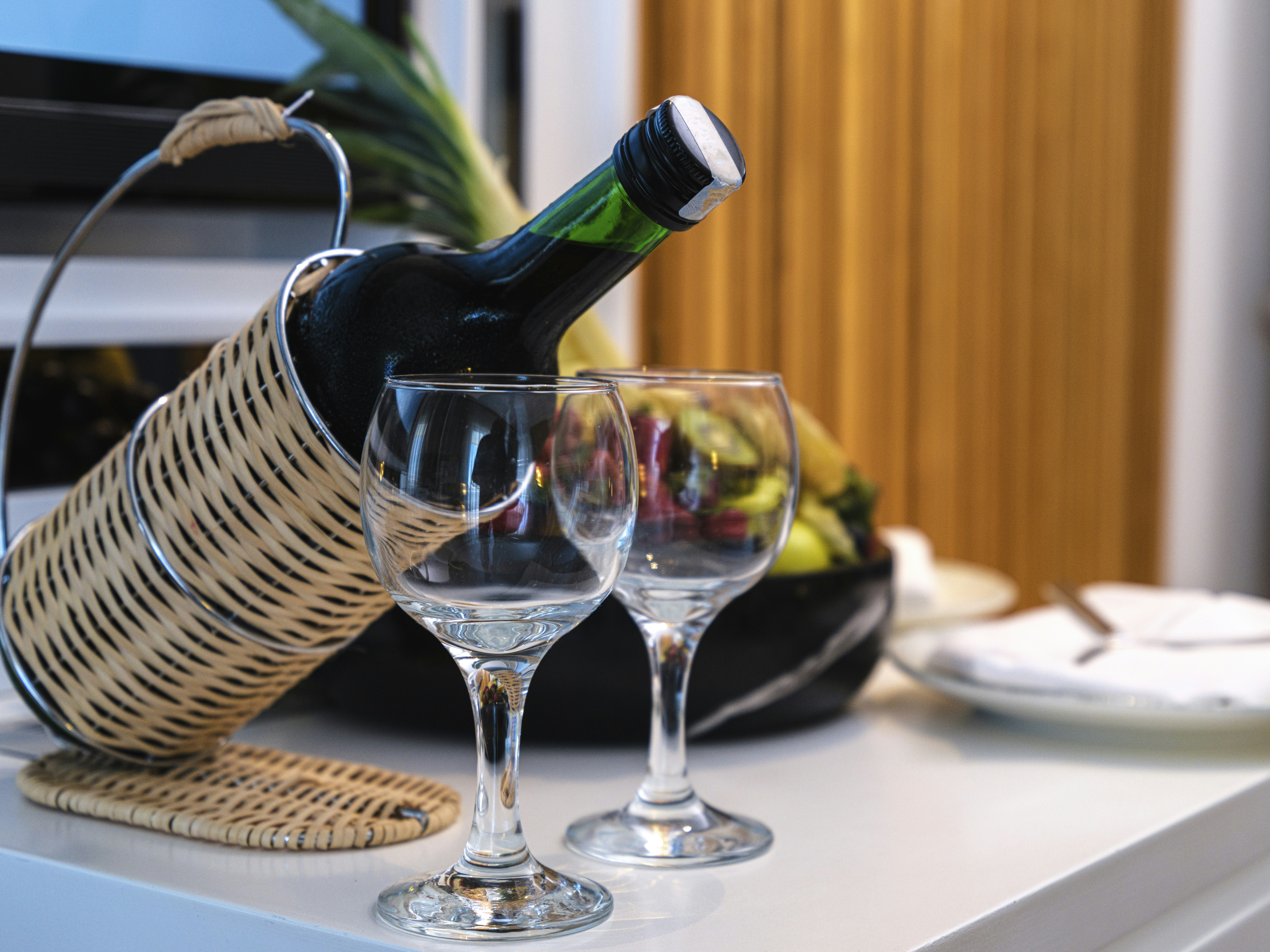 a basket with wine glasses, wine and fruits in the honeymoon room