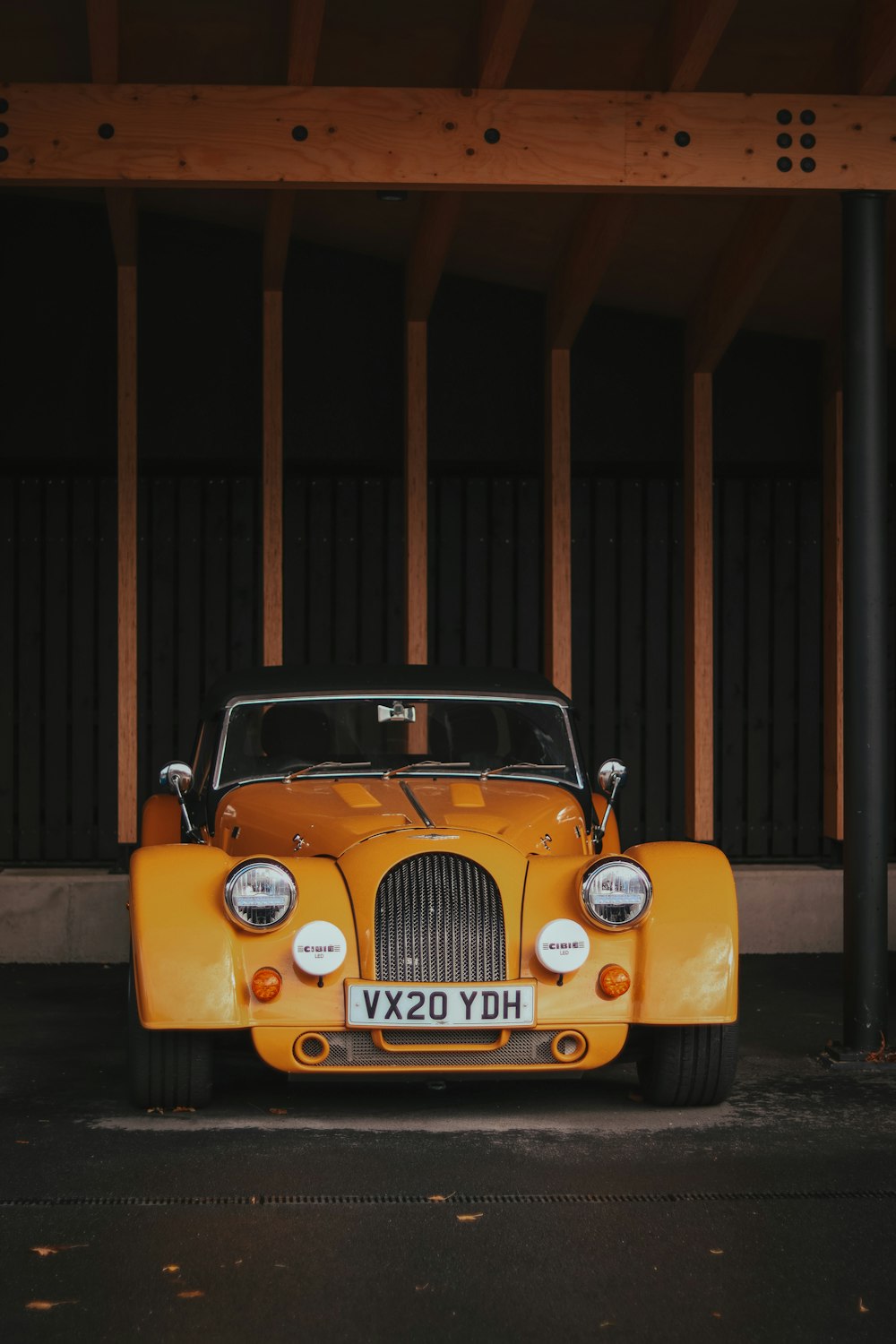 une voiture jaune garée sous une structure en bois