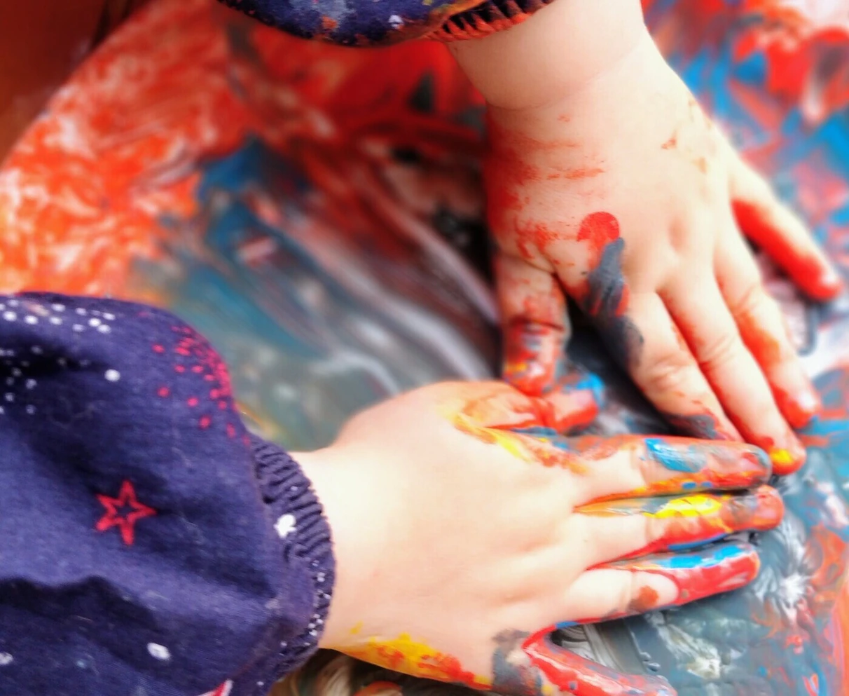 Dos manos pequeñas cubiertas de pintura de colores sobre una superficie