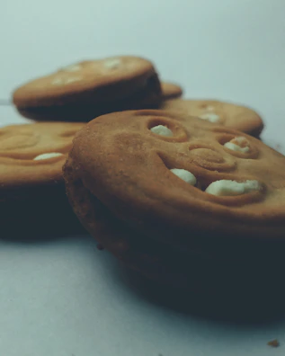 Two oatmeal cream sandwich cookies stacked neatly, showing soft textured oats and creamy vanilla filling.