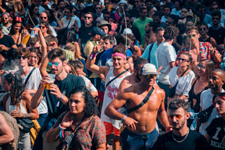 A lively crowd gathered at an outdoor summer festival, smiling and enjoying the event.