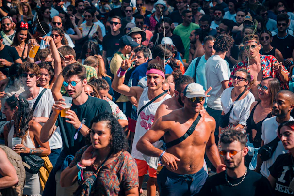 A lively crowd gathered at an outdoor summer festival, smiling and enjoying the event.
