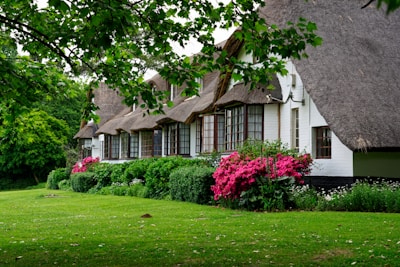 Cottage with flowering plants around the porch in a peaceful village setting.