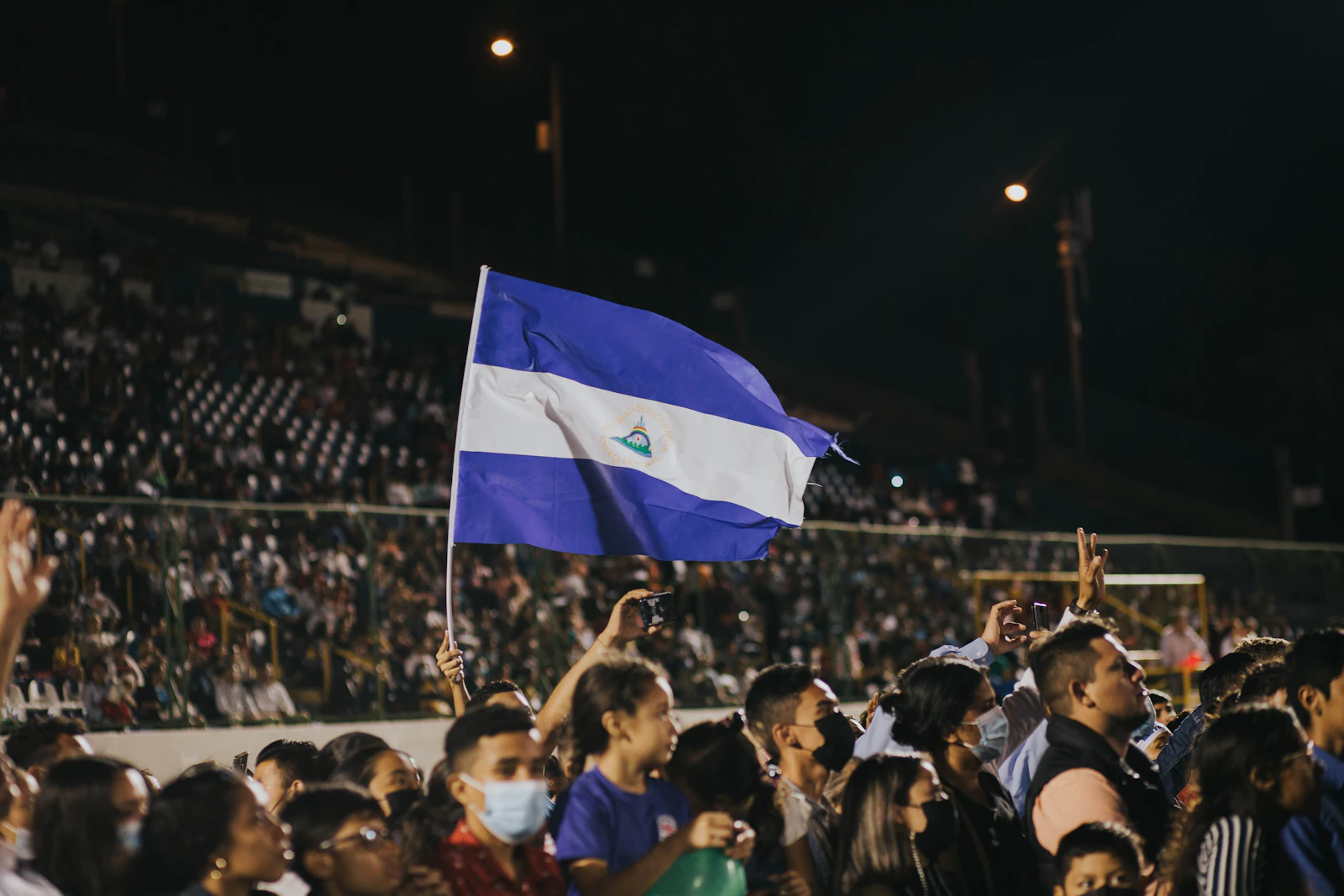 Supporters packed together waving national flags at a fan festival