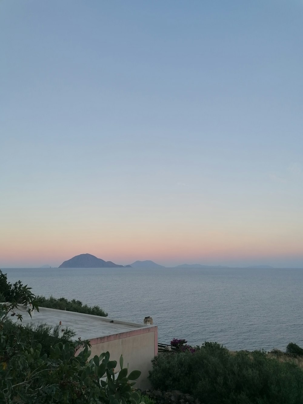 a body of water with a land with plants and a hill with a hill in the distance