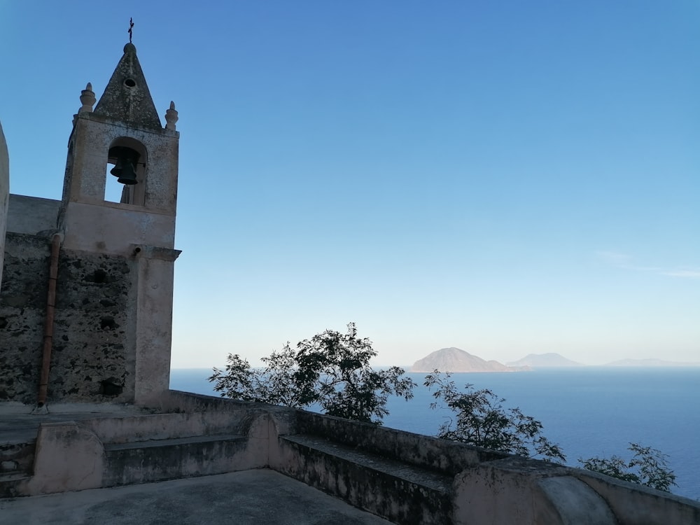 a bell tower on a hill overlooking a body of water