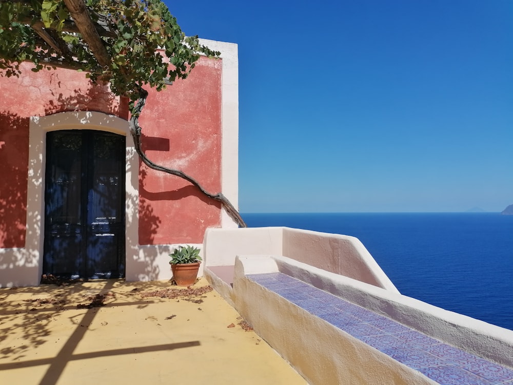 a building with a blue door and a tree with a white wall and a blue sky