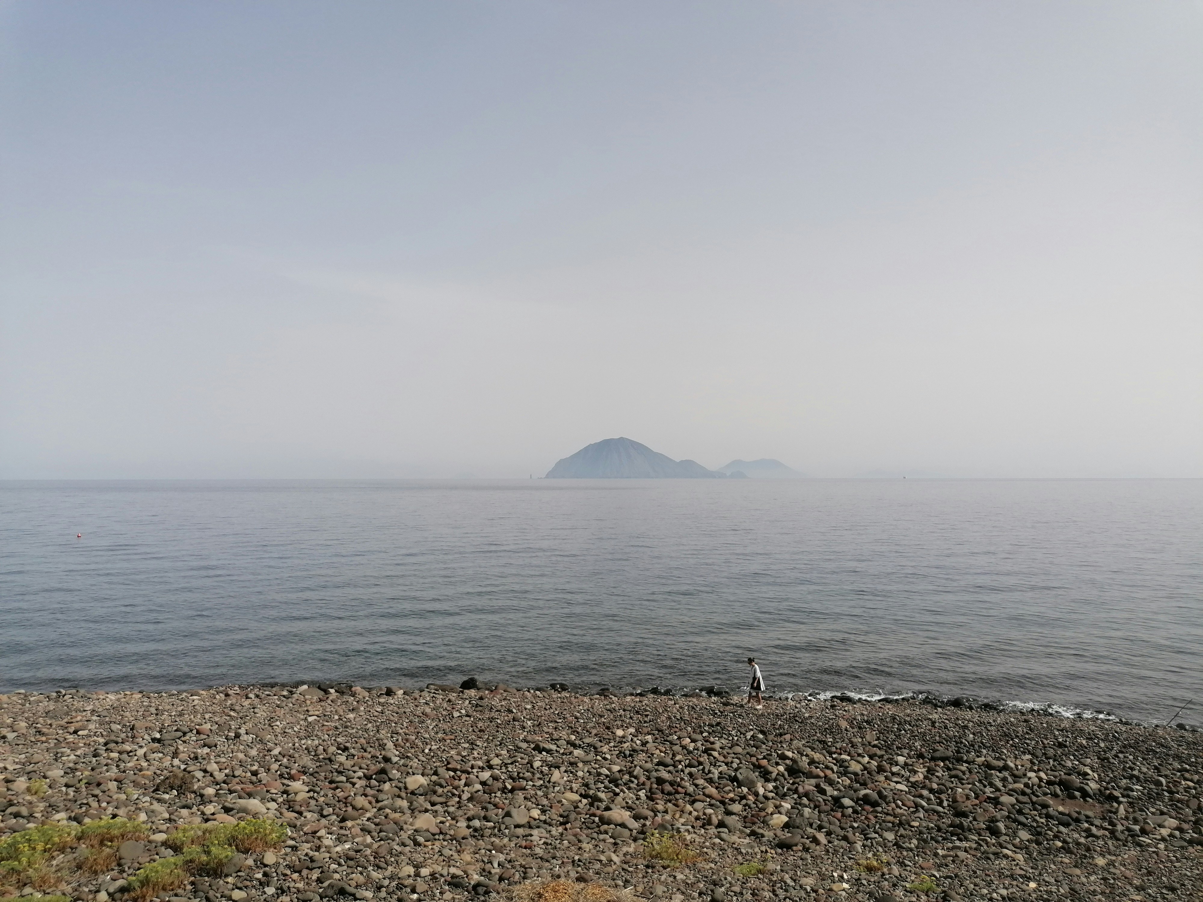 a rocky beach with a large island in the distance