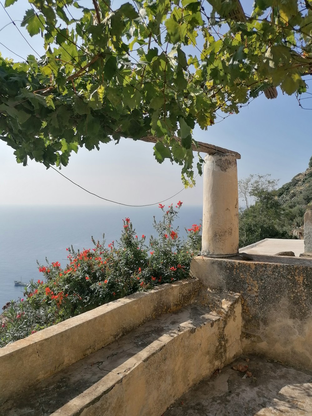 a stone wall with a stone pillar and a tree with flowers