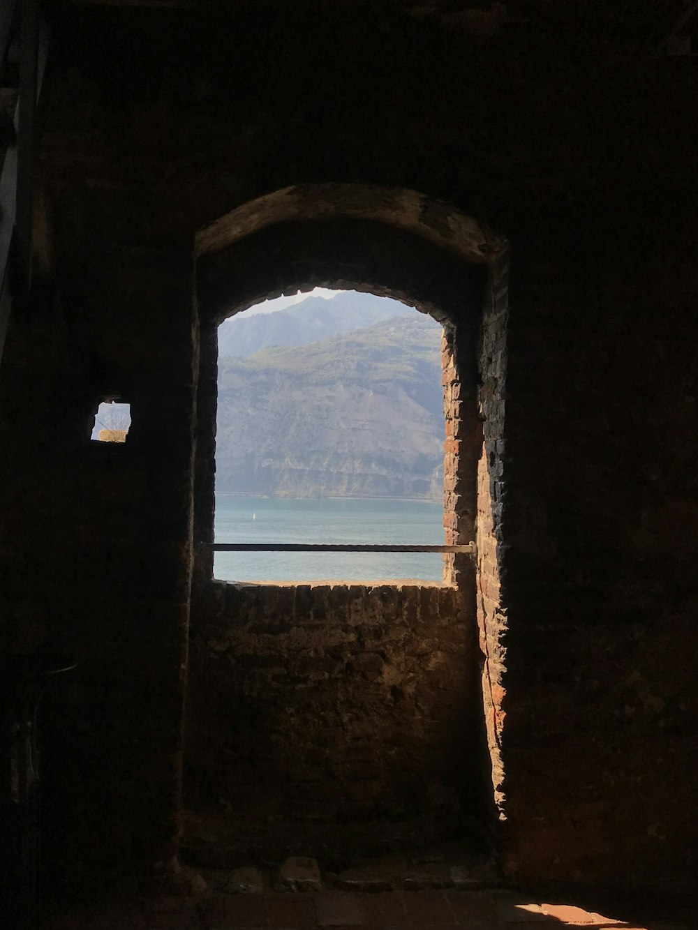 a stone archway with a view of a mountain and a lake