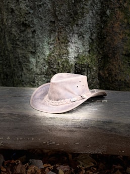 Close-up of a handcrafted western hat resting on aged wood with soft natural light highlighting the leather details.