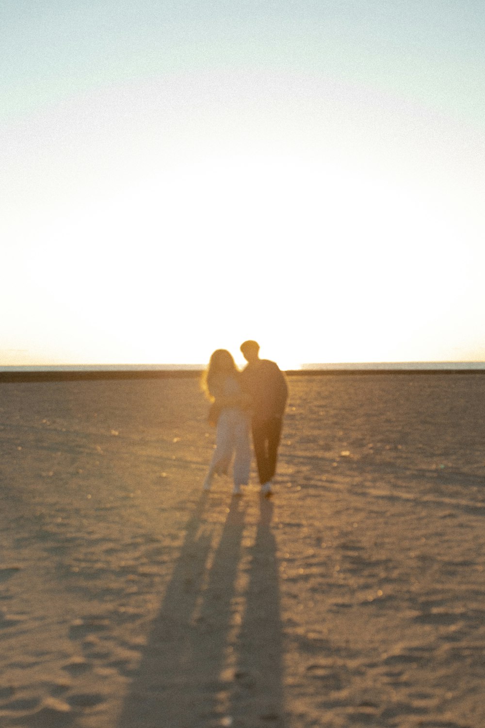 a man and woman kissing on a sandy beach