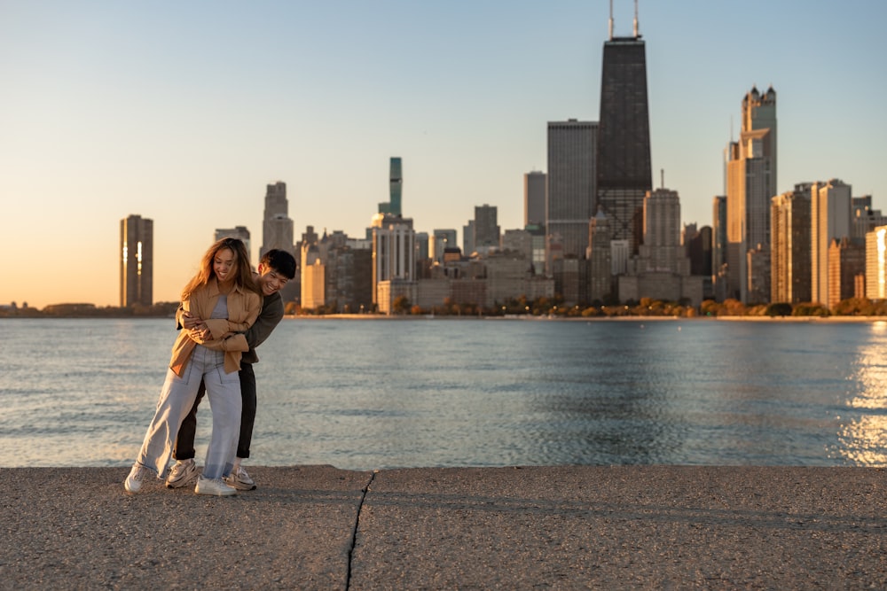 a man and woman posing for a picture next to a body of water