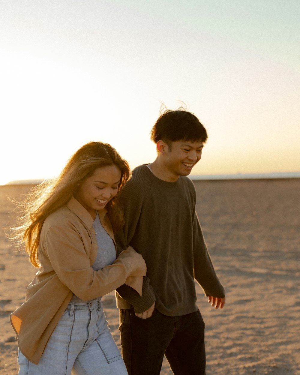 a man and woman holding each other on a beach