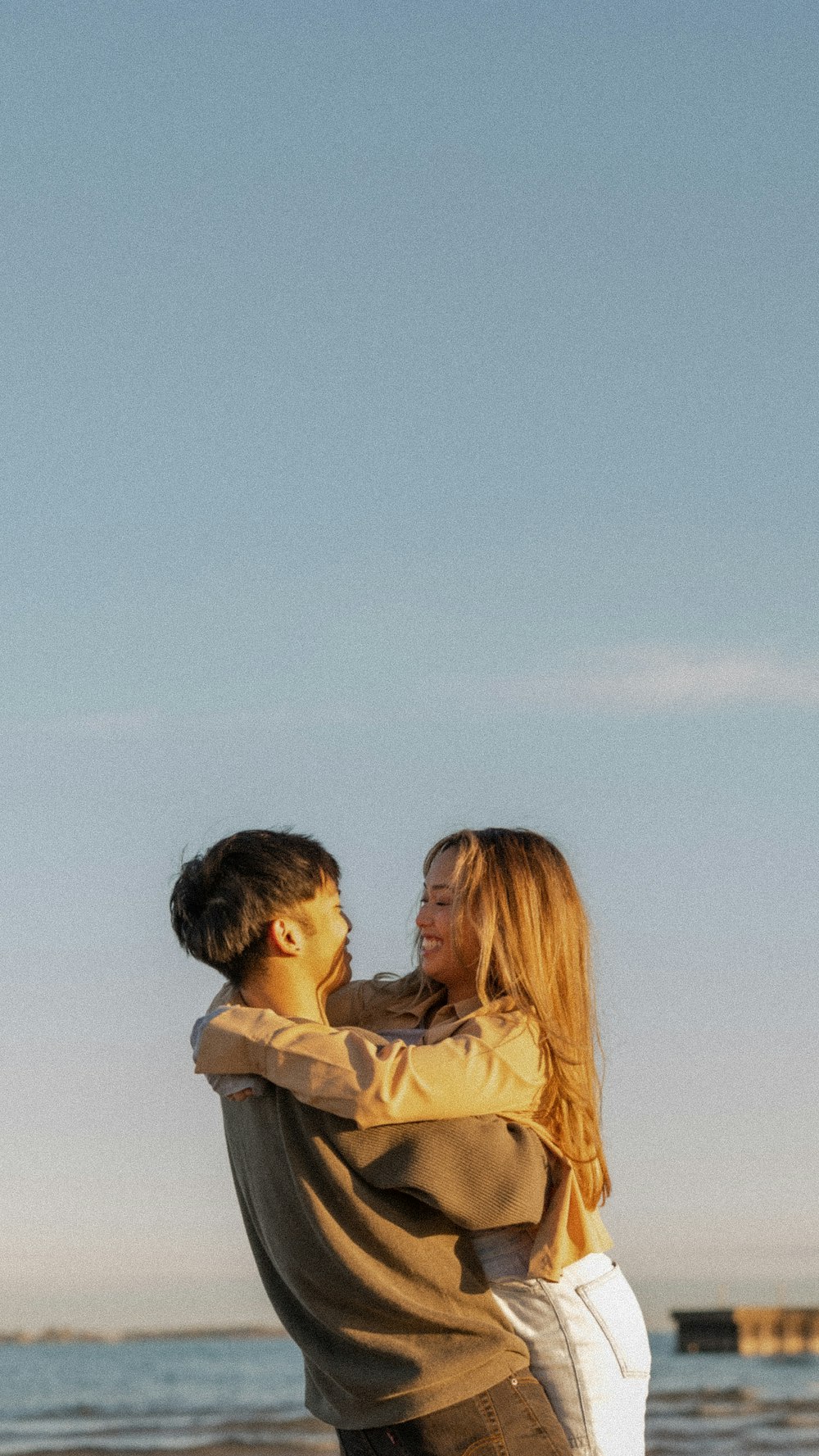 a man and woman hugging on a beach