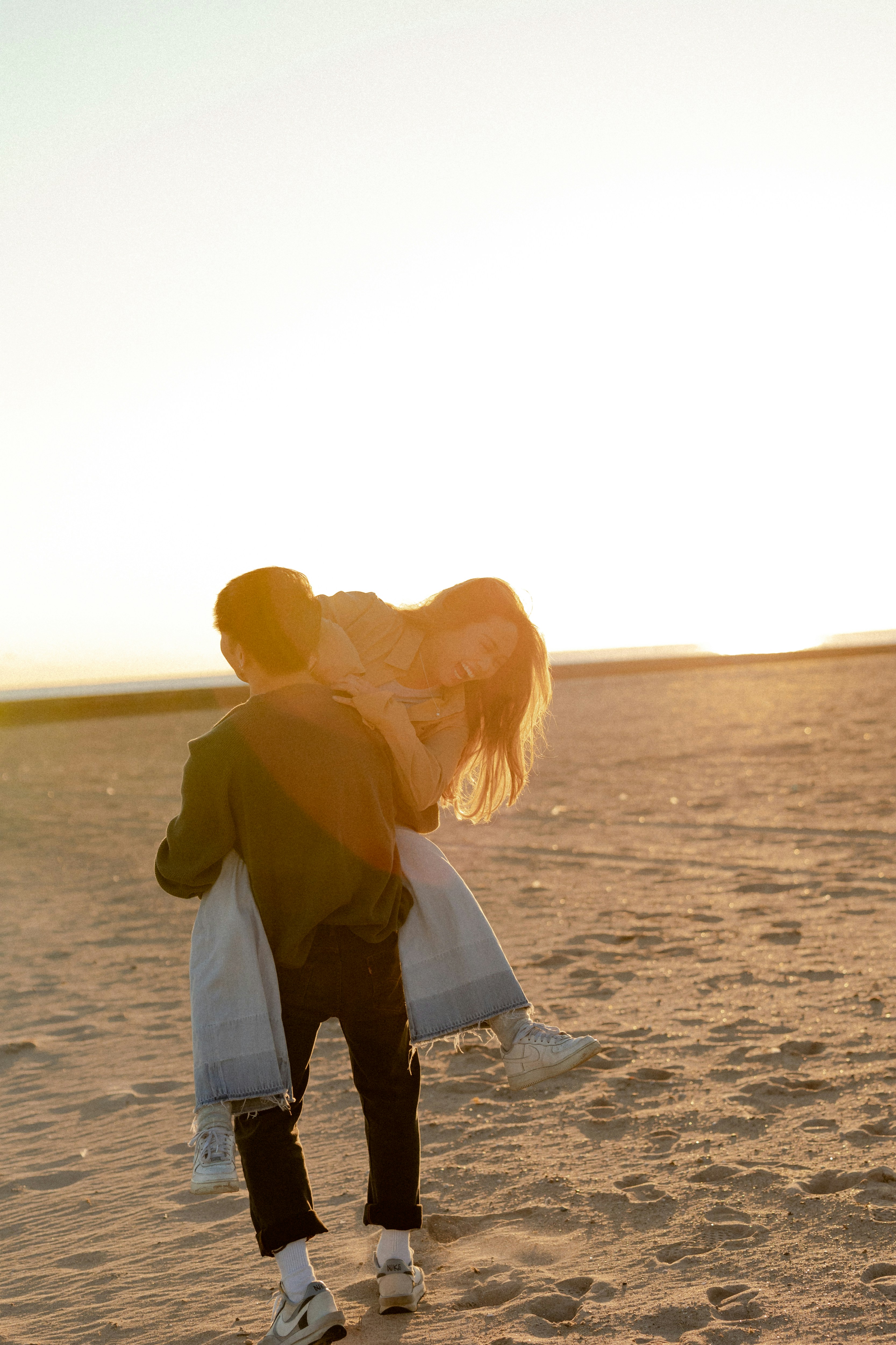 a man and woman kissing on a sandy beach