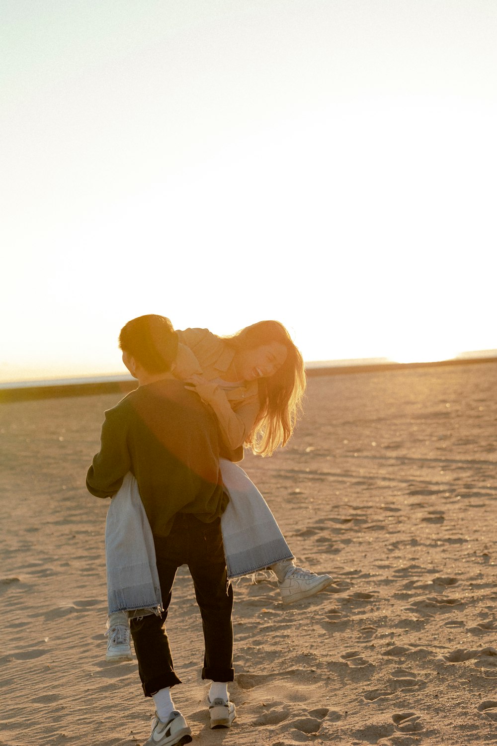 a man and woman kissing on a sandy beach
