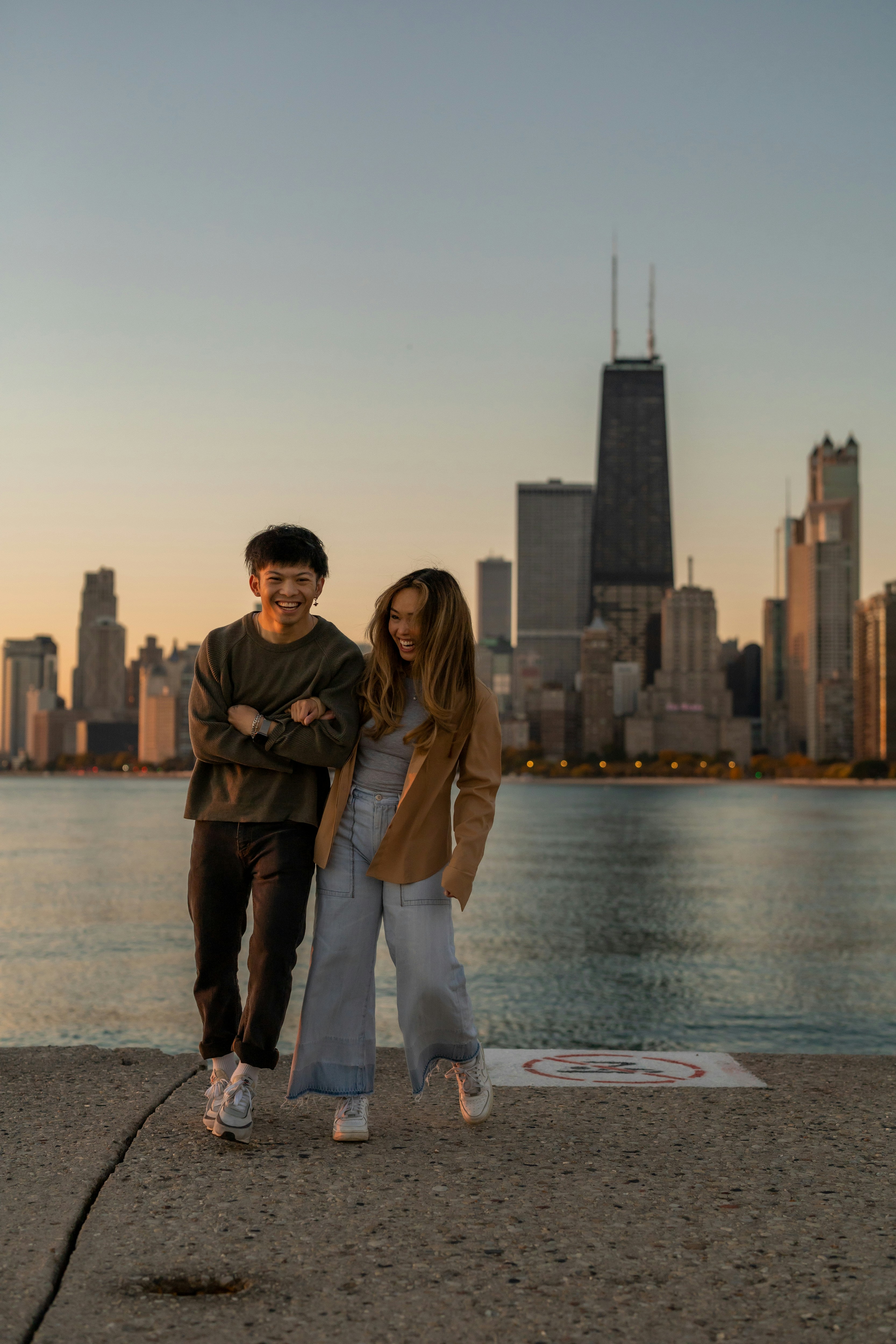 a man and woman posing for a picture in front of a body of water