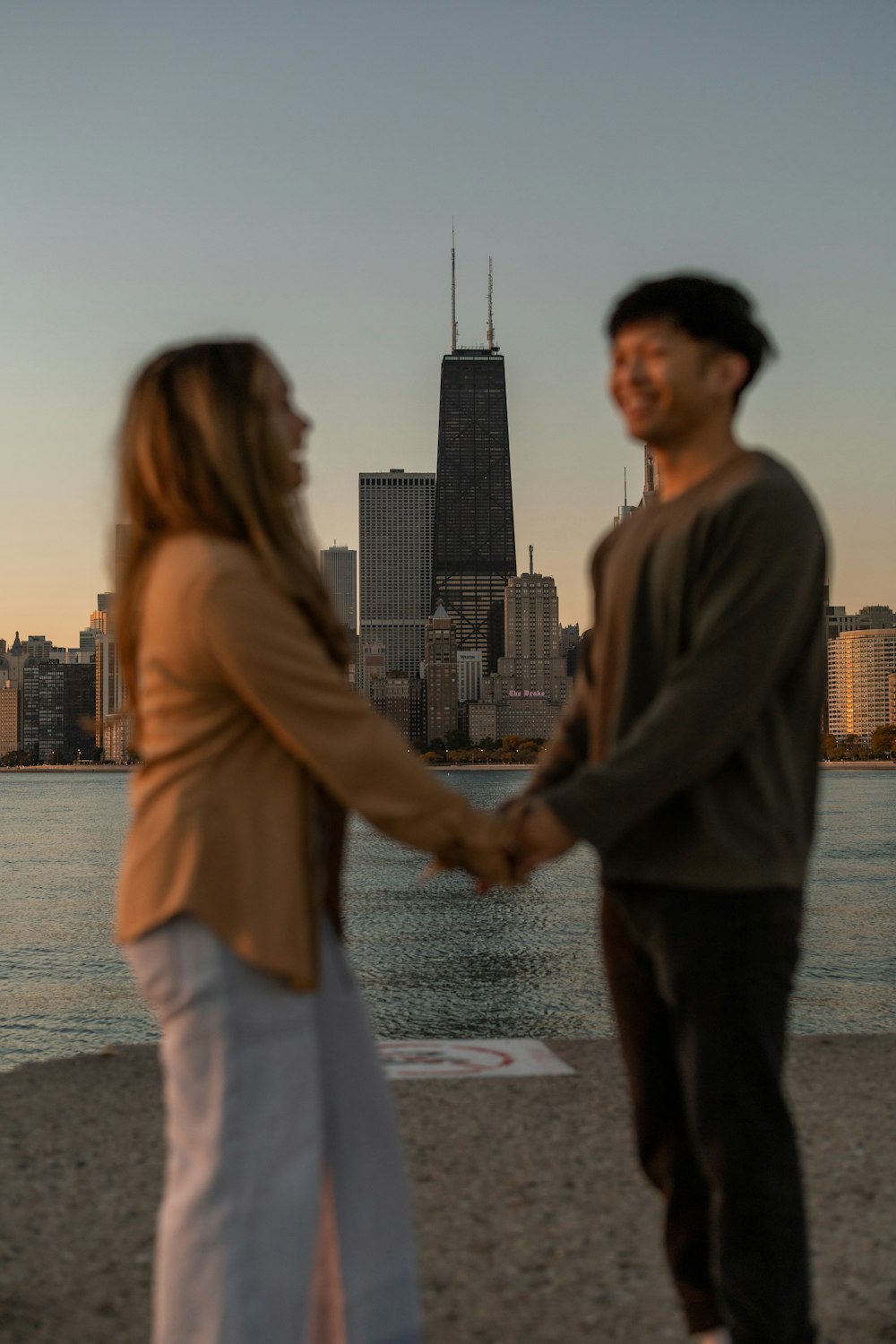 a man and woman shaking hands on a beach with a city skyline in the background