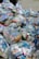 A large pile of household waste, primarily consisting of plastic bags filled with various types of cartons and bottles. The waste is organized in transparent bags with visible branding and labels.
