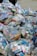 A large pile of household waste, primarily consisting of plastic bags filled with various types of cartons and bottles. The waste is organized in transparent bags with visible branding and labels.