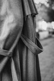 A close-up of a tailored women's coat hanging on a wooden hanger.