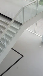 Modern glass railing on a staircase with clean aluminum supports and natural light.