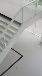 Photo of a modern staircase with clear glass railings letting in natural light.