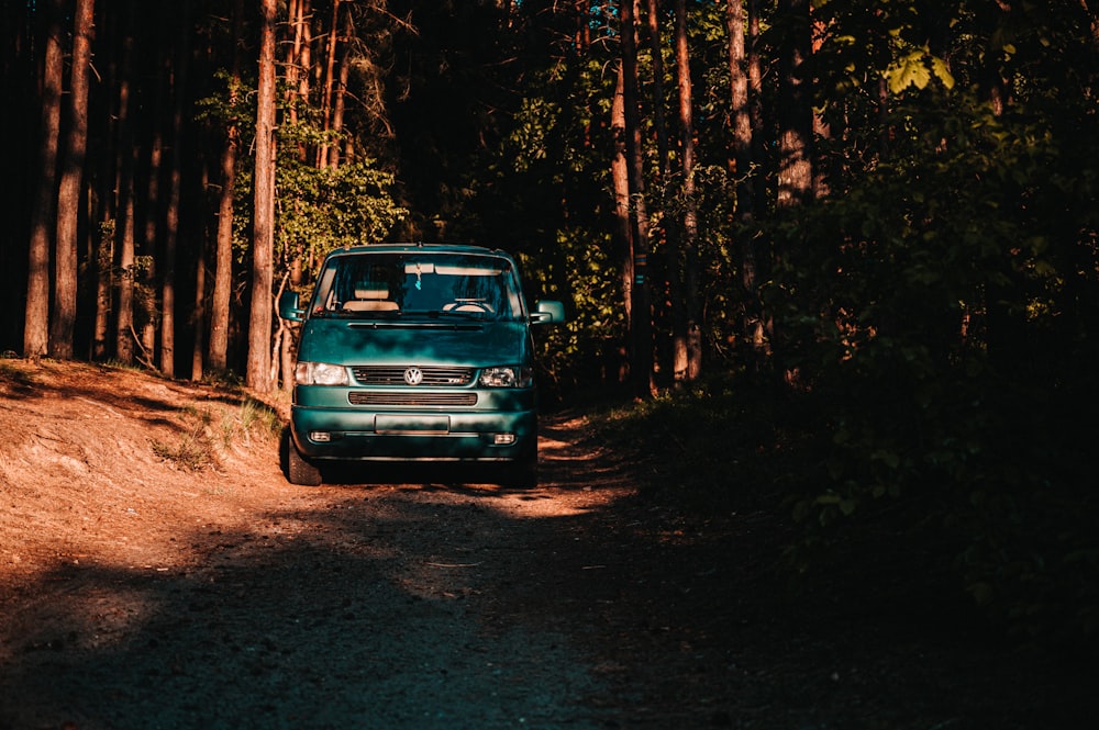 a car driving on a dirt road in the woods