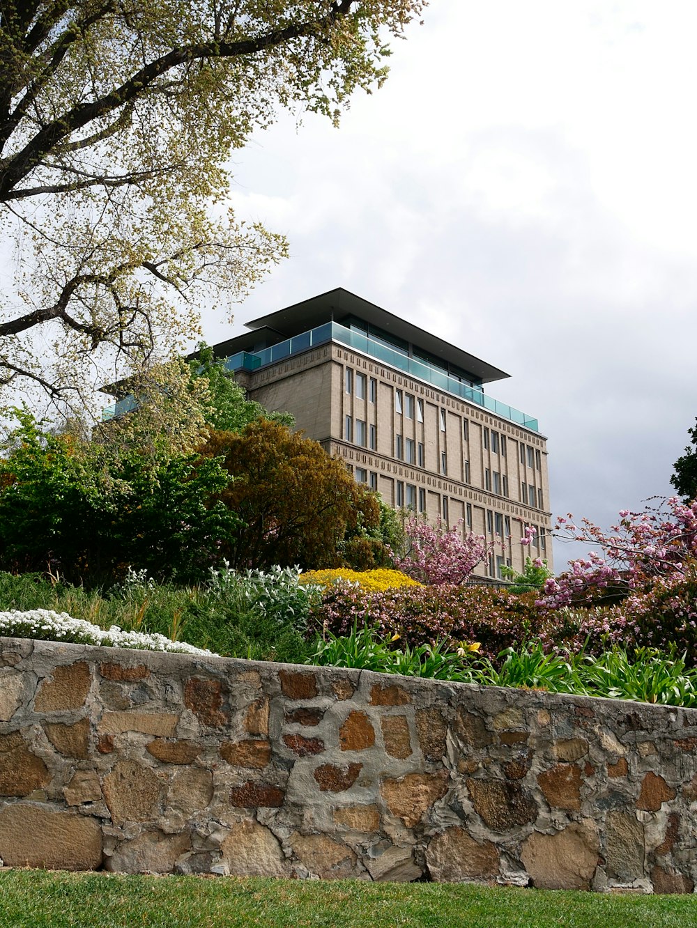 a building with a stone wall and trees in the front