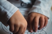 a person's hand holding a pen over a paper with a cat on it