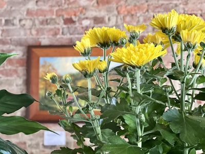 A bright yellow floral painting in a minimalistic black frame.