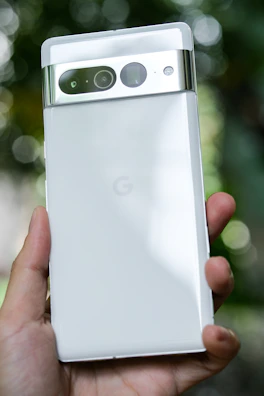A hand holding a slim smartphone with a futuristic holographic interface.